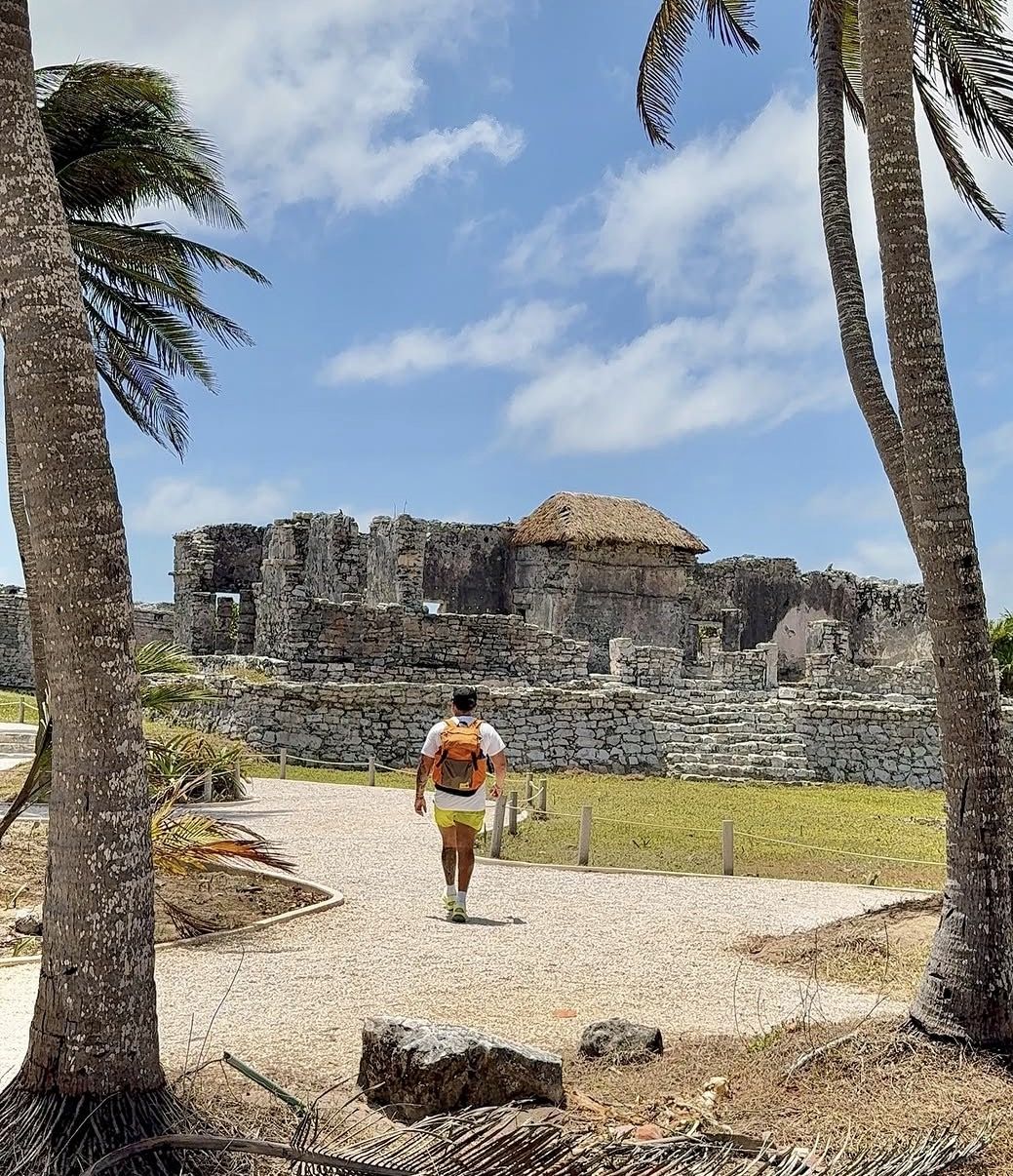 Visitor applying sunscreen and drinking water at Tulum Ruins in hot tropical weather